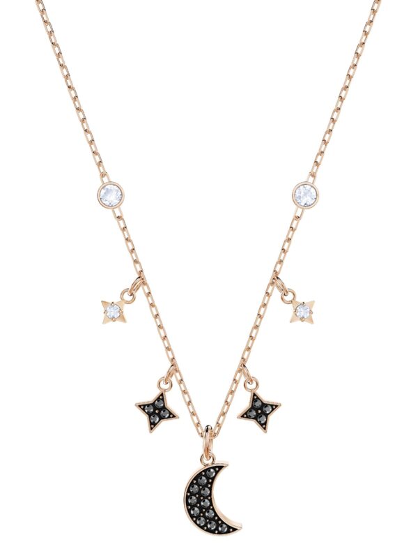 A close-up of the Swarovski Symbolic Moon Necklace, showcasing a rose-gold tone chain with a shimmering moon pendant and star charms, adorned with black and white crystals. 